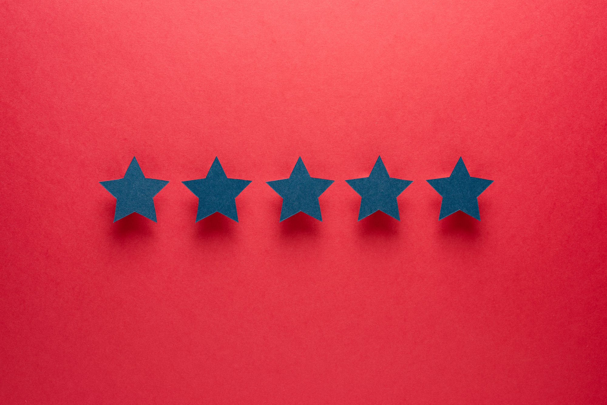 Feedback concept. Five blue paper stars of approval on a red background.